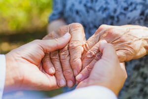 holding elderly shaking hands